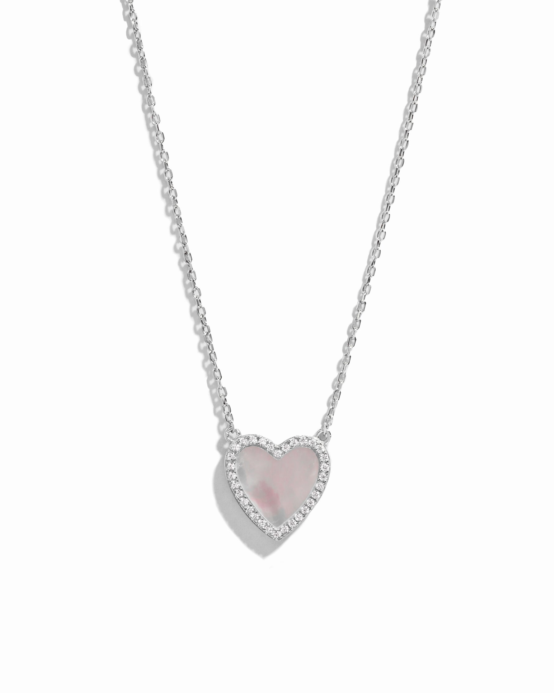 A close-up of the heart necklace showing its radiant mother of pearl surface and delicate  silver chain.