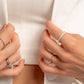 model wearing silver rings featuring an opal studded eternity ring, a silver open spiral ring, a diamond baguette ring, and a pearl ring