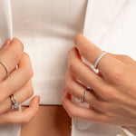 model wearing silver rings featuring an opal studded eternity ring, a silver open spiral ring, a diamond baguette ring, and a pearl ring