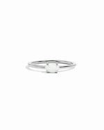 Silver ring with a small opal solitaire stone on a white background
