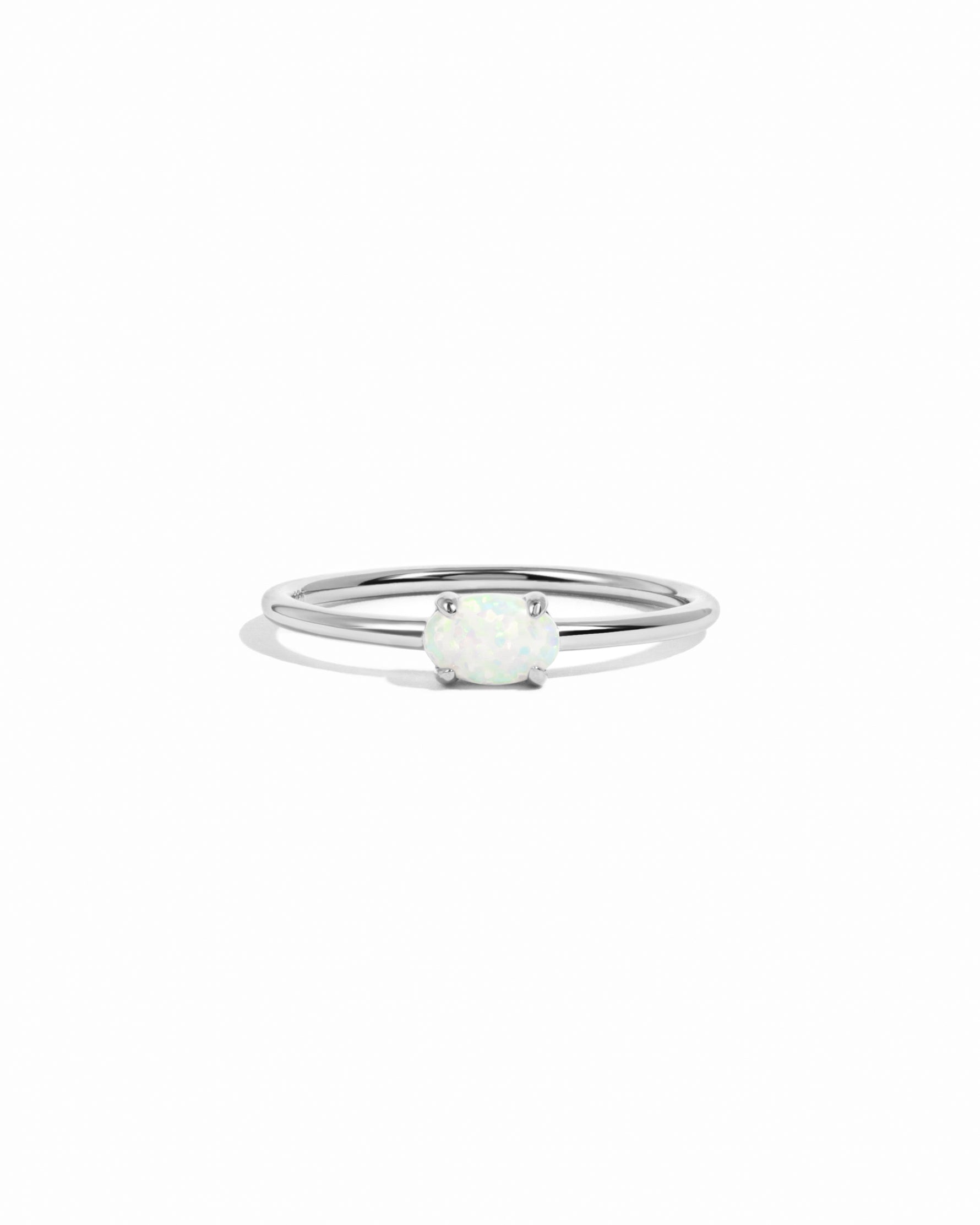 Silver ring with a small opal solitaire stone on a white background