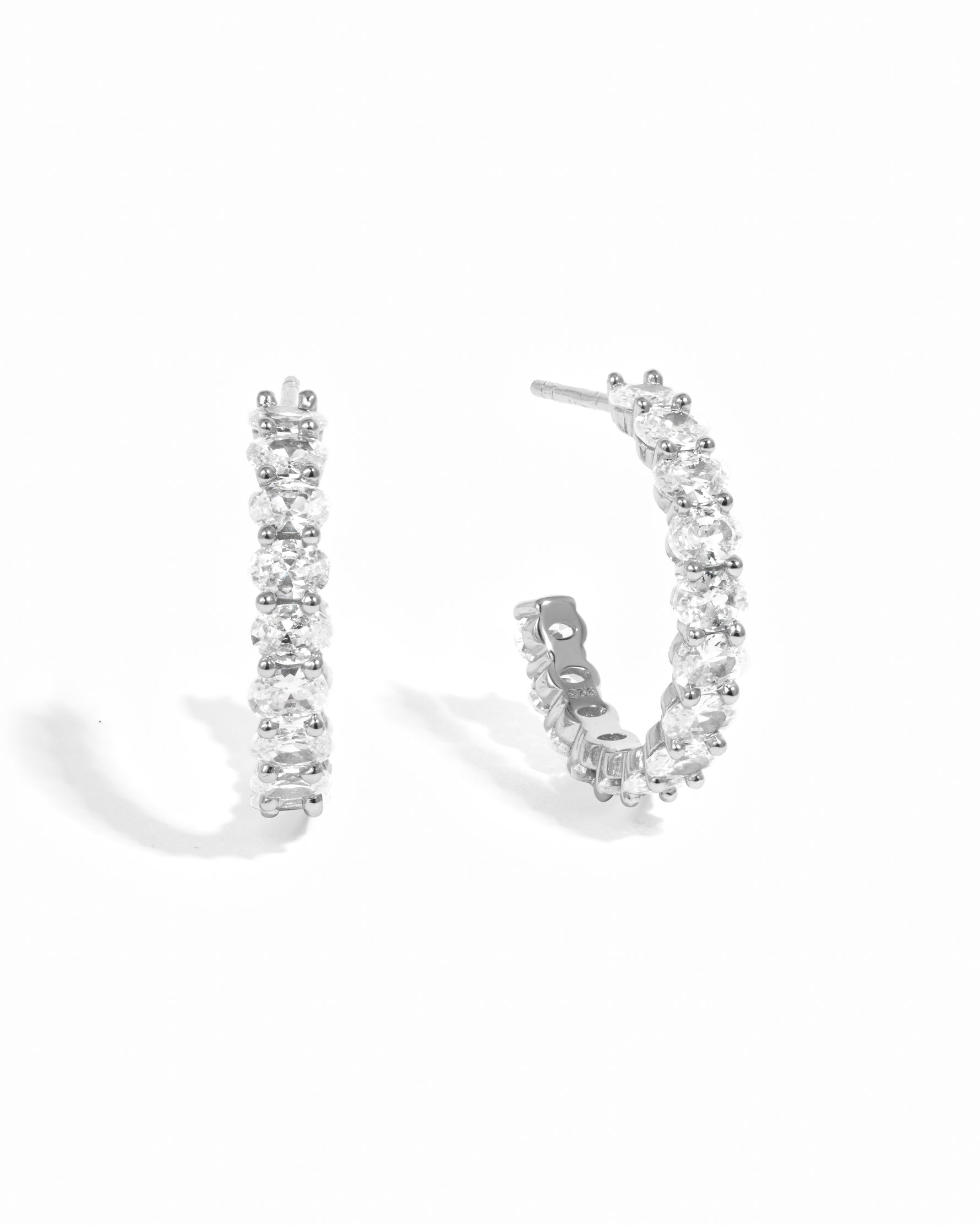 Silver hoop earrings with white cz stones on a white background