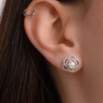 Model wearing silver stud earrings with flower earring design and pearl earring design