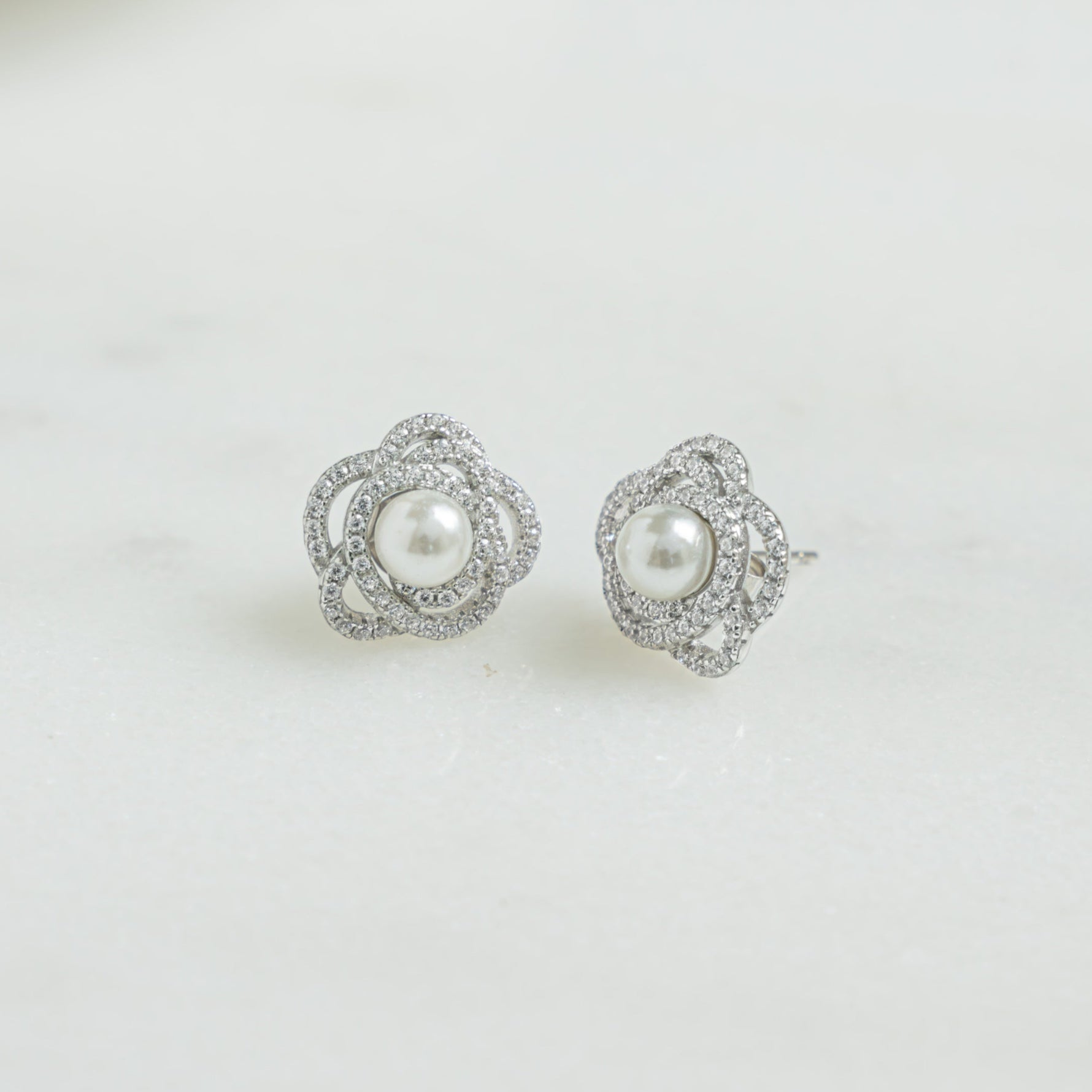 Closeup image of sterling silver stud statement earrings with floral design and pearl earring design