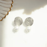 close-up image of silver spiral earrings with a dangle drop freshwater pearl