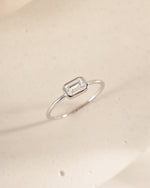 Sterling silver ring with a baguette gemstone on a light beige background