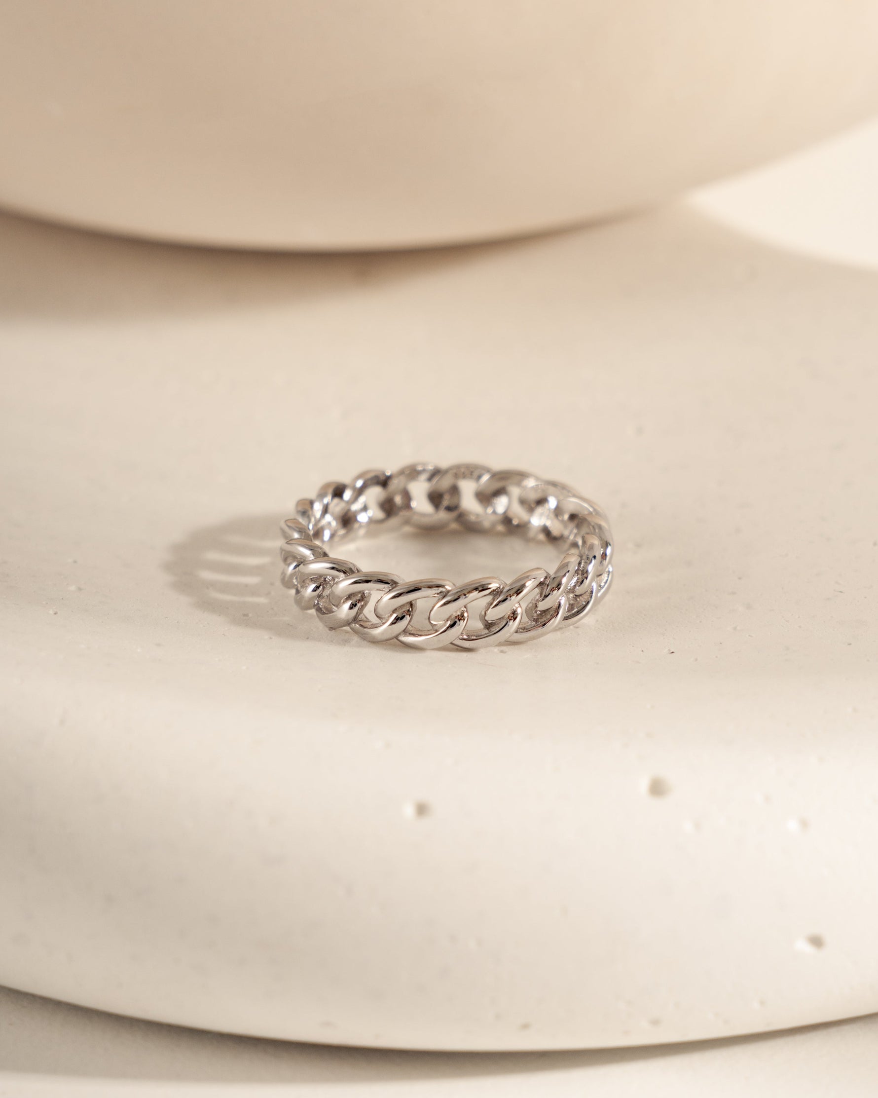 Silver chain ring on a white ceramic surface
