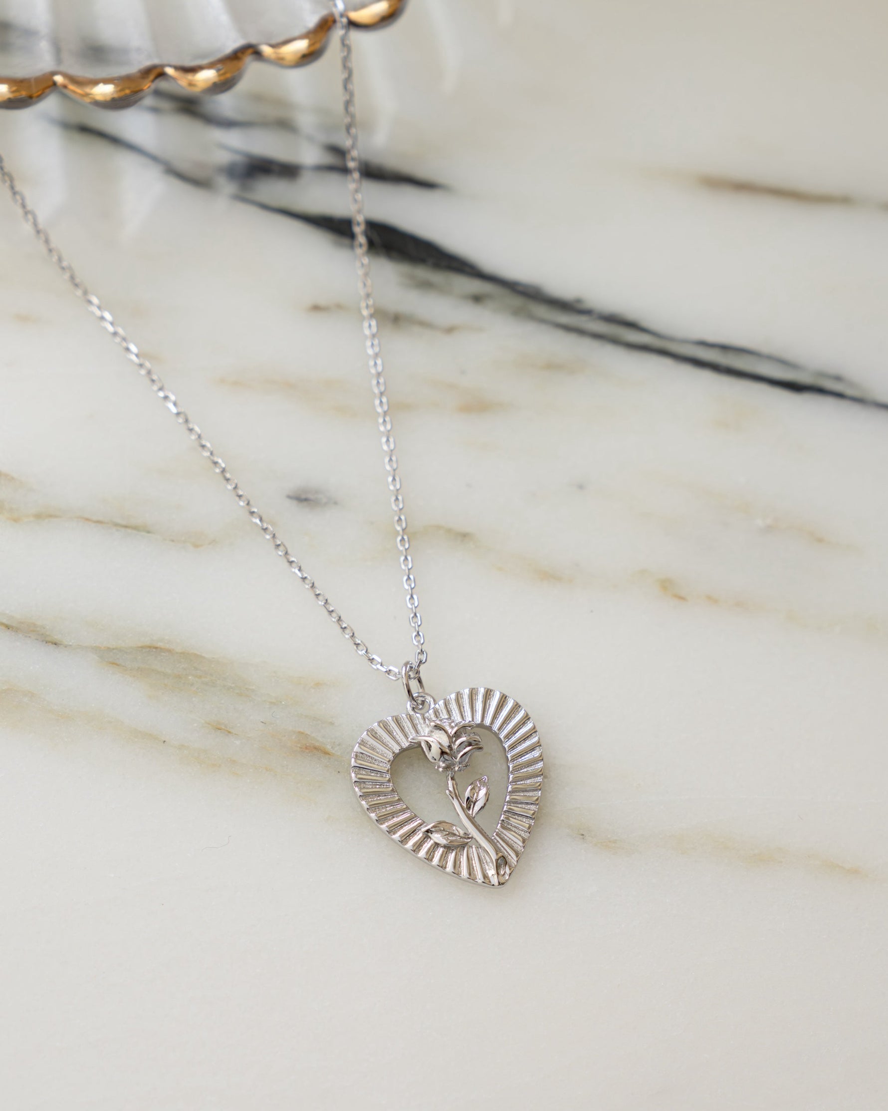 Silver chain rose necklace on a marble background