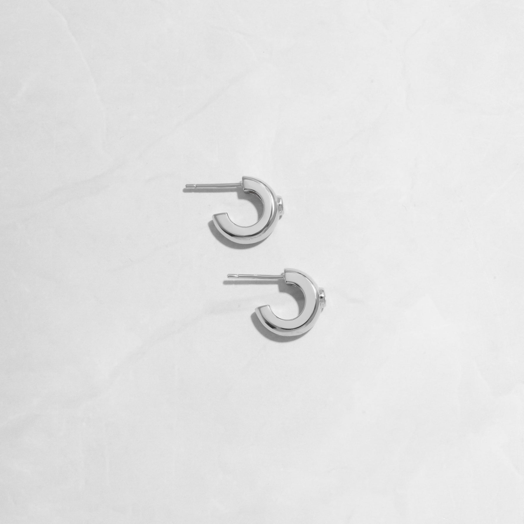 Closeup flatlay image of silver small chunky hoop earrings