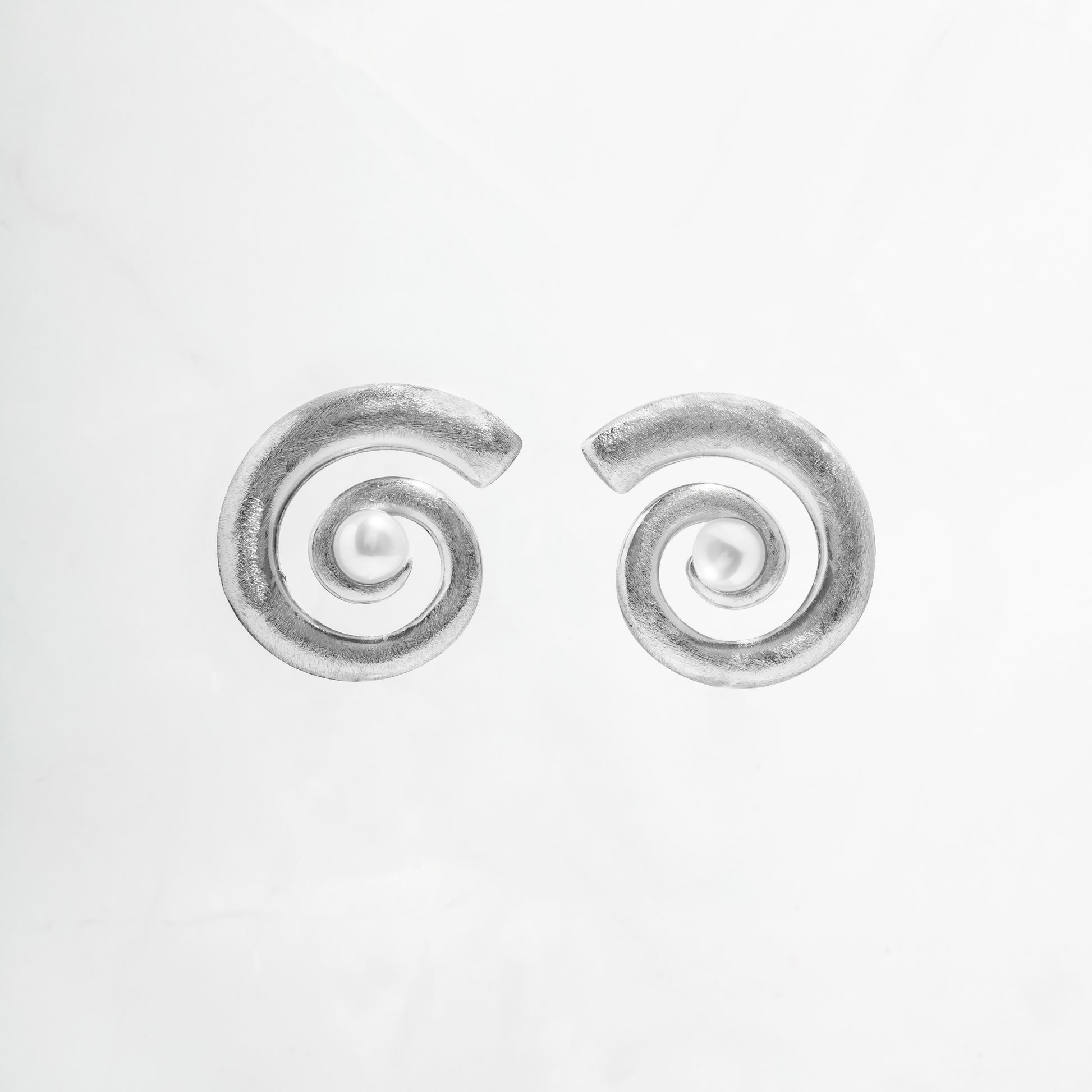 closeup image of earrings for summer featuring a spiral earring design and freshwater pearl
