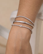 Model wearing sterling silver bracelet stack featuring two silver diamond tennis bracelets and a diamond bangle bracelet