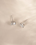A pair of silver studs on a neutral background