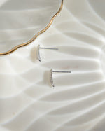 Sterling silver tiny earrings on a plain surface