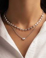 Model wearing diamond pendant necklace styled with a silver layering diamond tennis necklace 