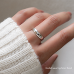 a close up of a models hand wearing a plain silver ring that can be used as a wedding band