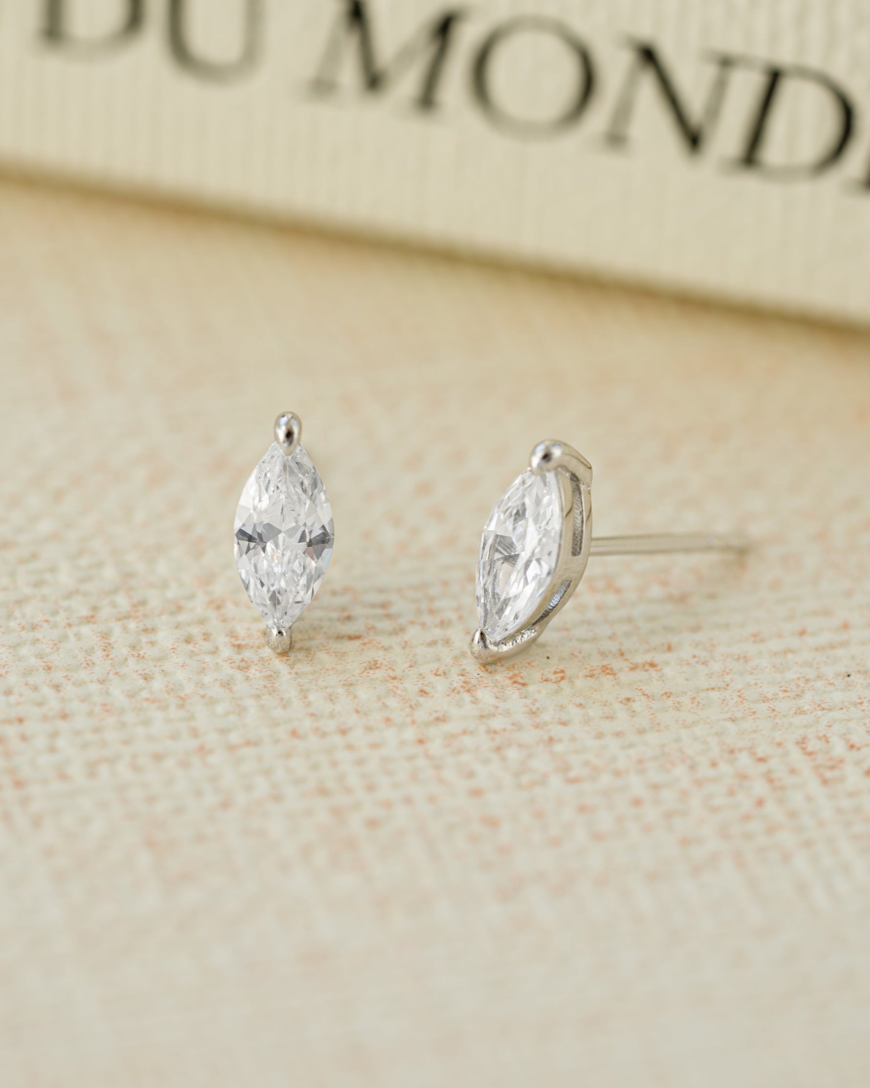 Sterling silver cubic zirconia earrings on a beige background