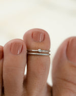Close-up of toes with a silver adjustable toe ring with a bezel set cubic zirconia stone