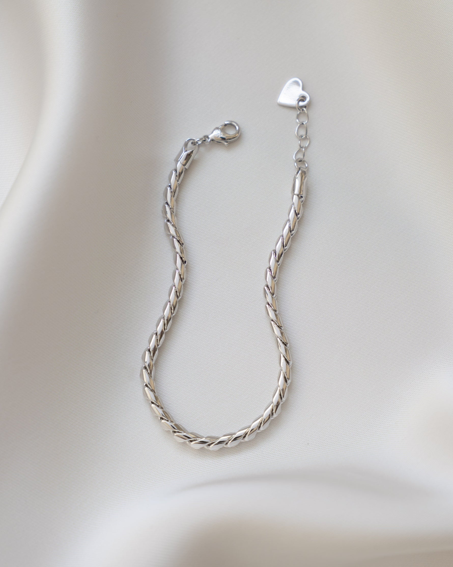Silver snake chain bracelet on a soft beige fabric background