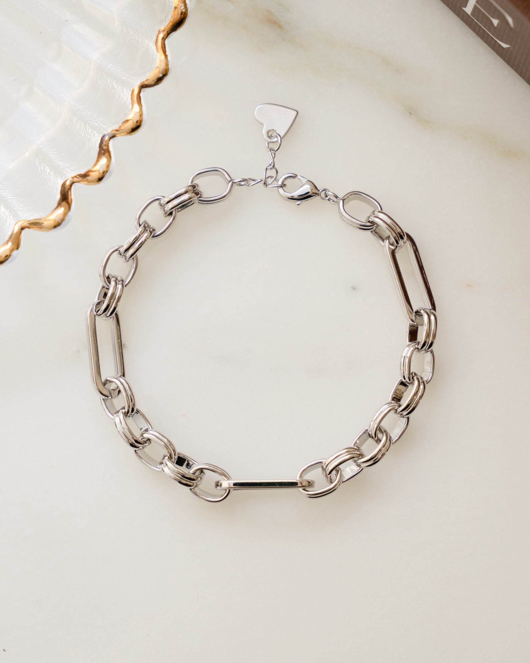 Silver statement jewelry chain bracelet on a marble surface 