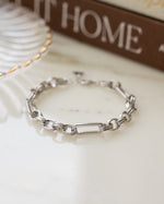Silver rolo chain paperclip bracelet on table