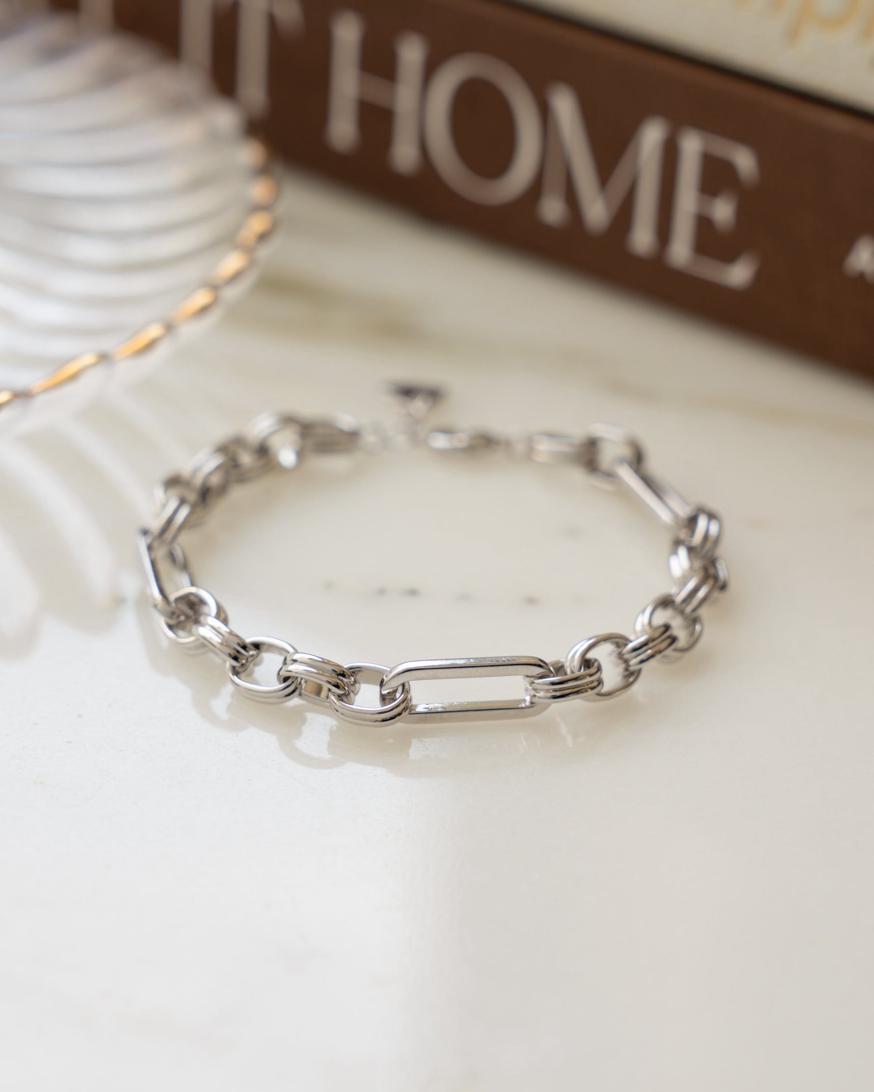 Silver rolo chain paperclip bracelet on table