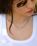 Model wearing silver choker necklace and silver layering necklaces, one silver chain necklace and one silver opal pendant necklace