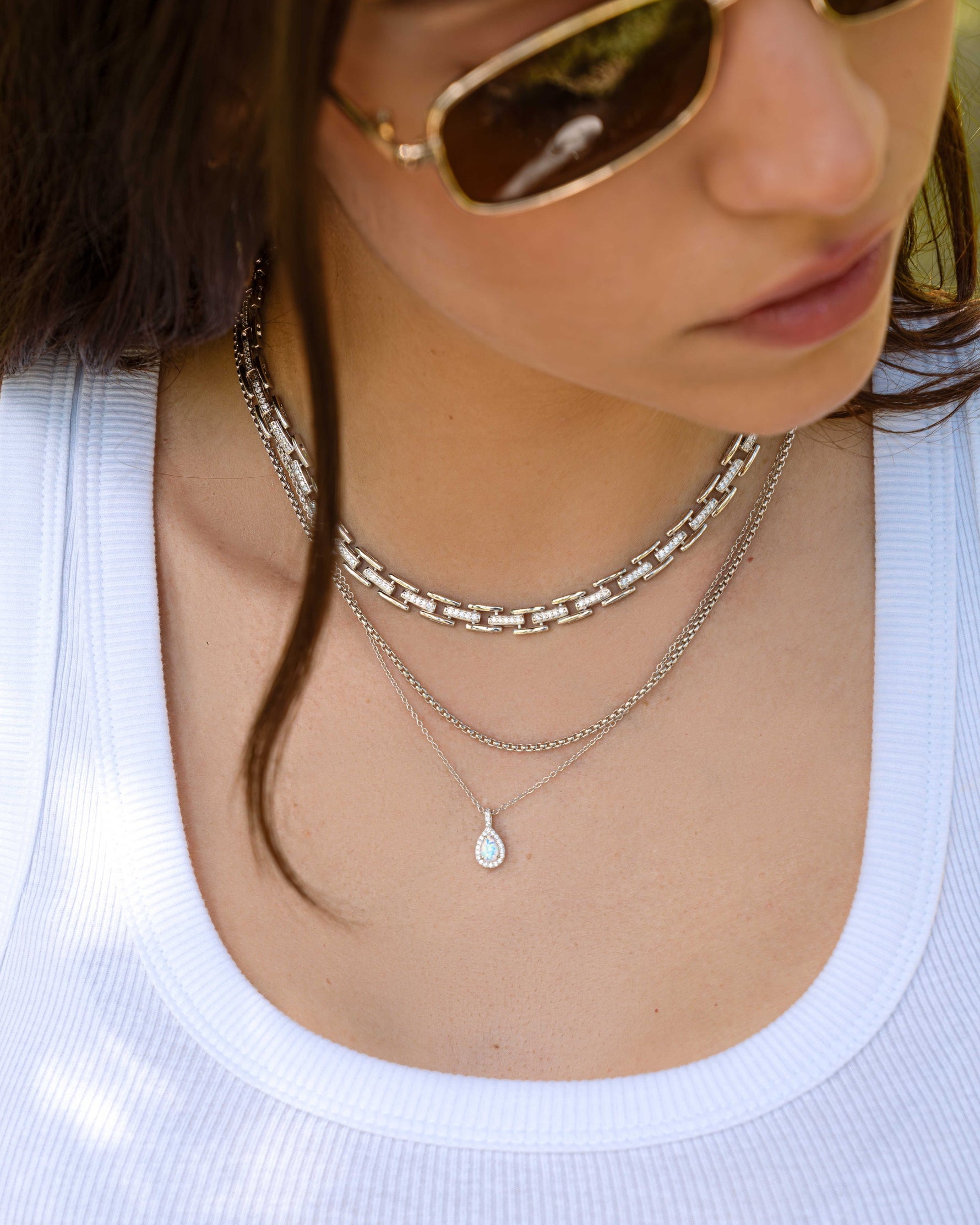 Model wearing silver choker necklace and silver layering necklaces, one silver chain necklace and one silver opal pendant necklace