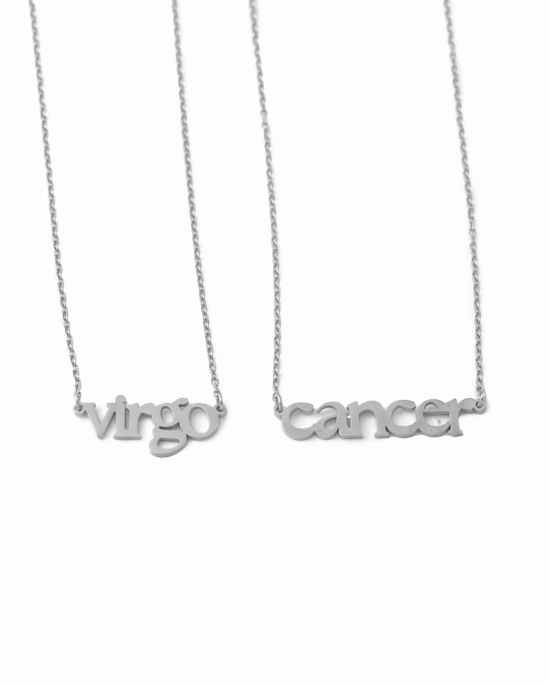 Two silver necklaces with 'virgo' and 'cancer' written on a white background