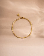 Gold adjustable minimalist bracelet on neutral background