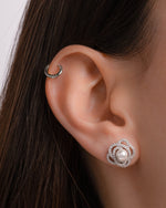 Close-up of an ear wearing a pearl earring and a silver hoop cartilage earring