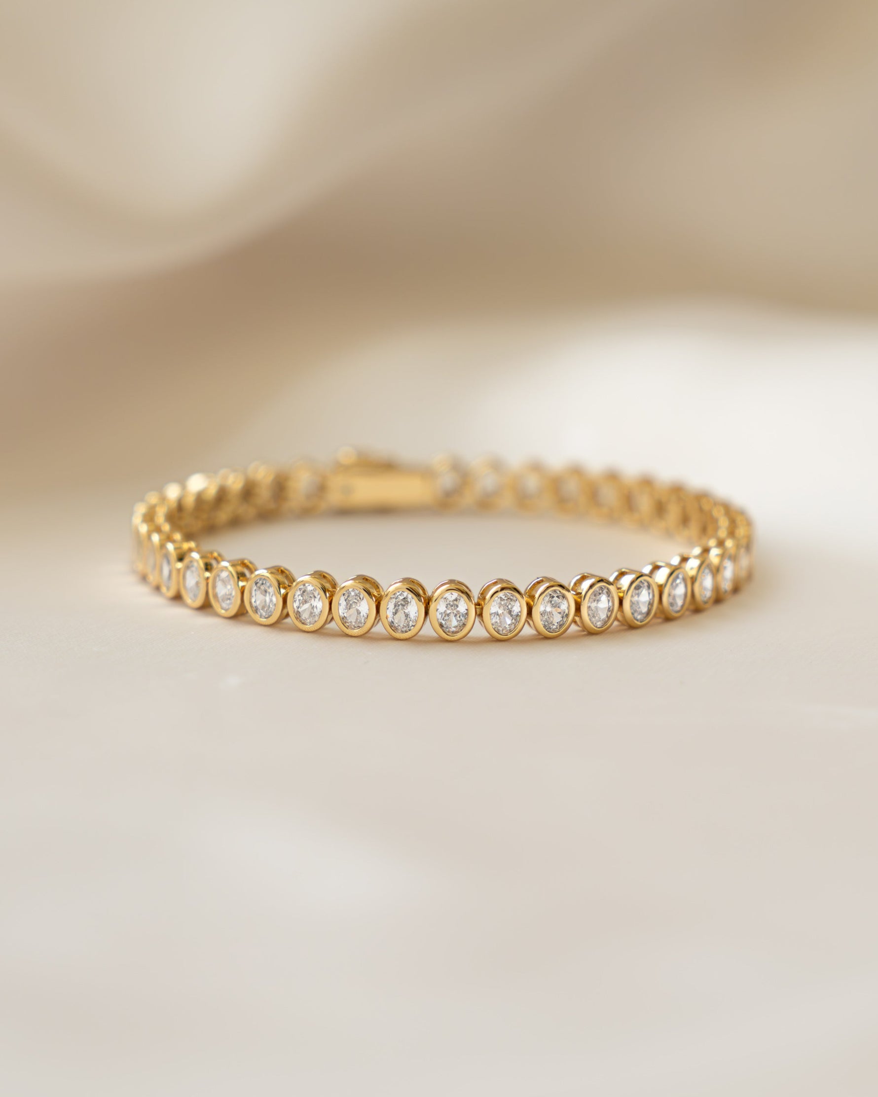 Gold bracelet with oval stones on a beige background