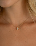 Close-up of a gold gemstone necklace with a small bezel diamond pendant