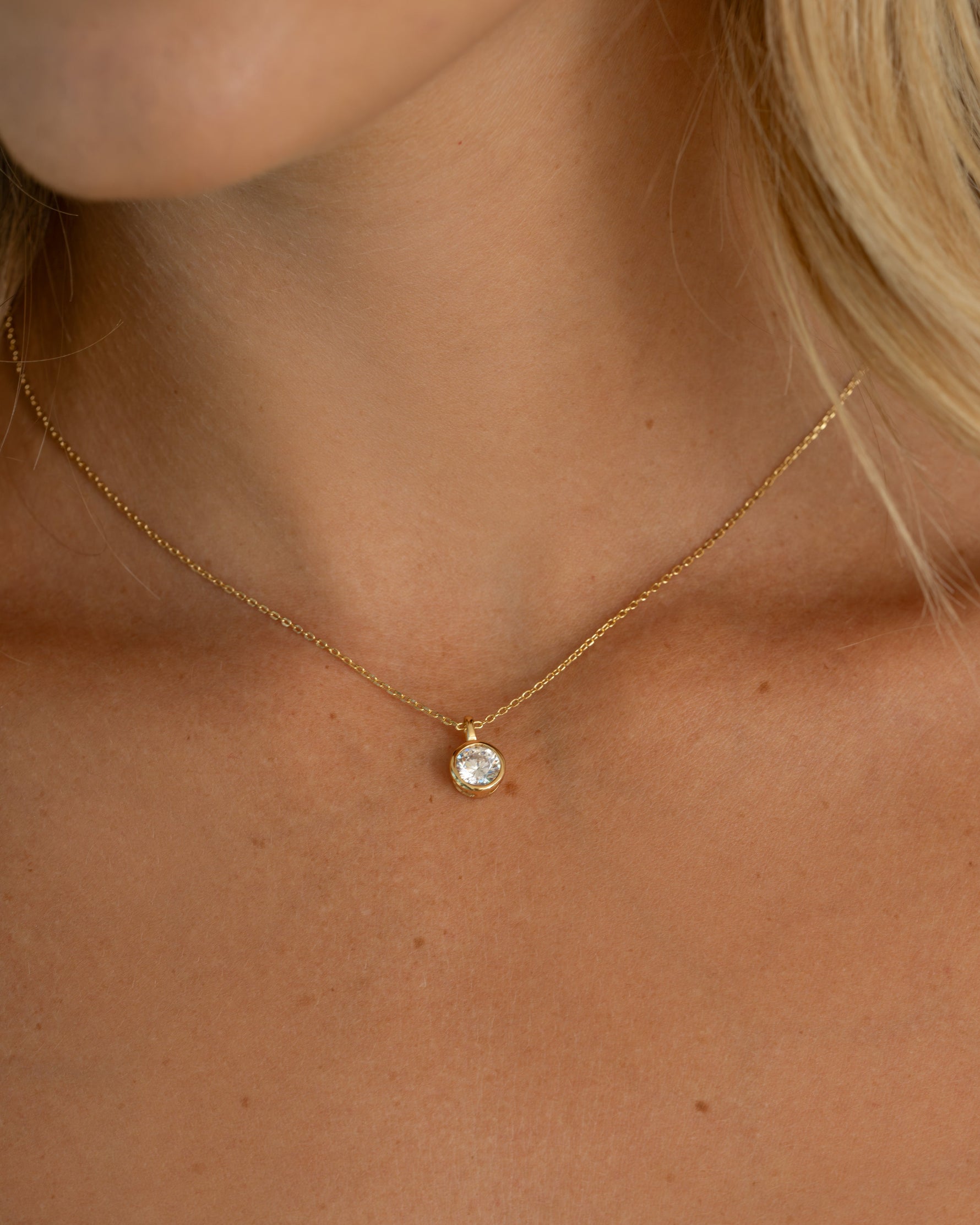 Close-up of a gold gemstone necklace with a small bezel diamond pendant