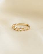 Closeup image of gold stacking diamond ring with bezel set diamonds and a textured ring design