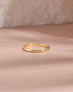 Gold stacking ring on a soft pink fabric background