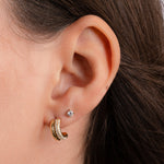 model wearing small hoop earrings featuring a gold hoop with cubic zirconia stones