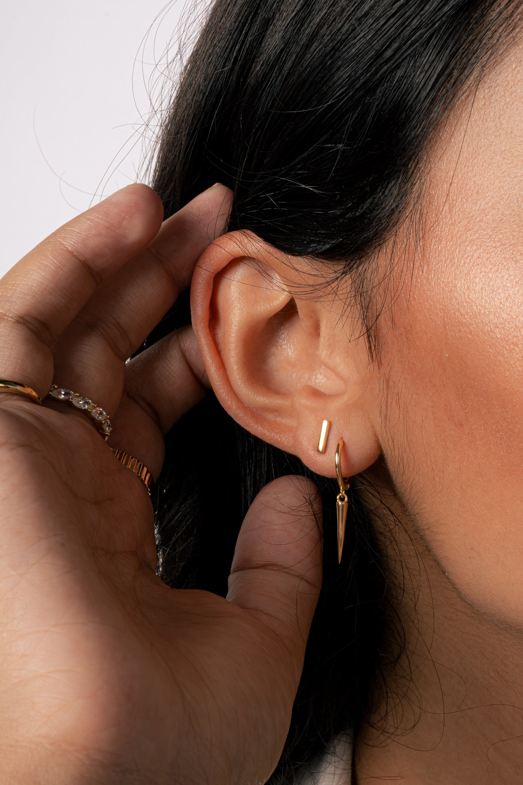 Model wearing gold plain bar studs with gold spike charm earrings