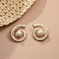 closeup image of drop statement earrings featuring spiral earring design and a freshwater pearl