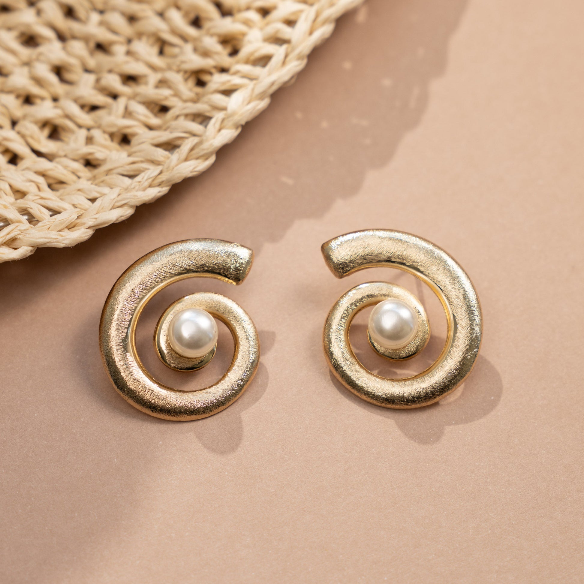 closeup image of drop statement earrings featuring spiral earring design and a freshwater pearl