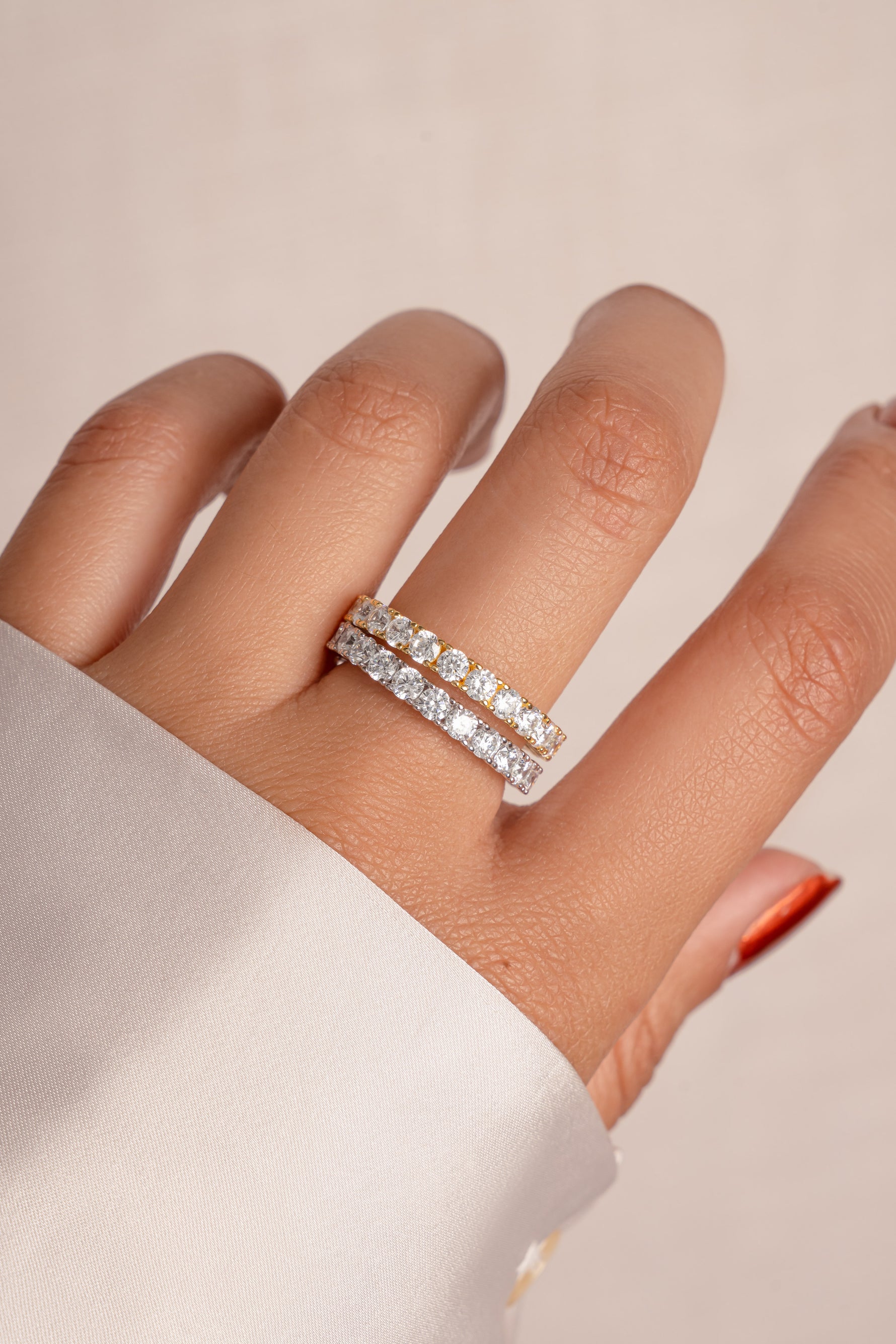 Model wearing gold and silver diamond eternity rings stacked. 