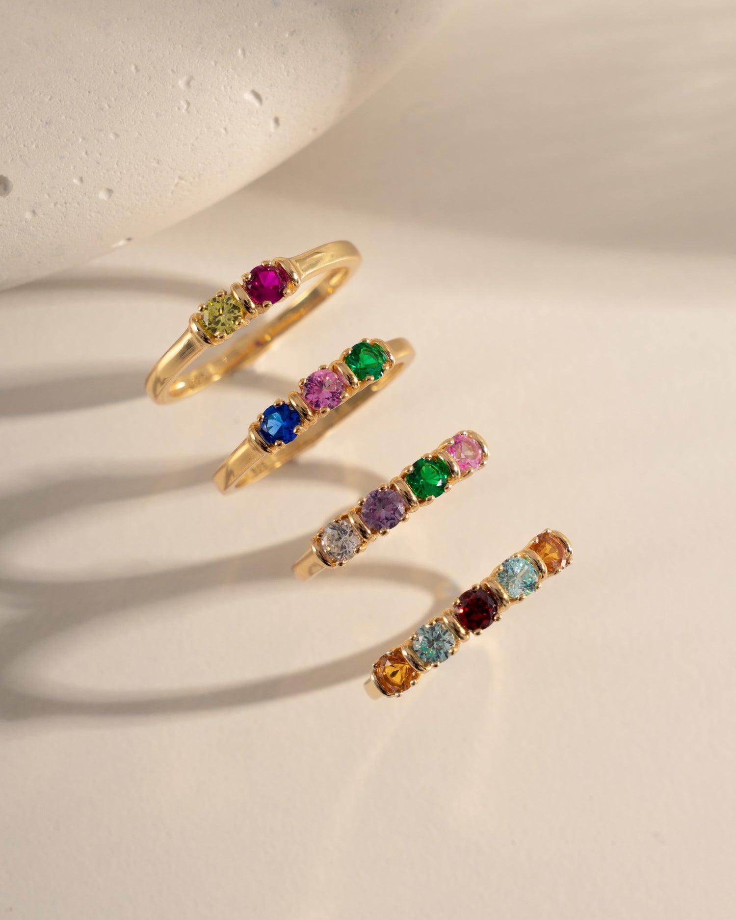 Set of gold rings with different birthstones gemstones on a light background