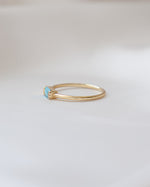 Thin gold ring with a baguette turquoise gemstone on a light background