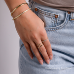 Model wearing gold band on the middle finger paired with diamond ring on the index finger,  styled with matching gold bracelet and diamond bracelet.