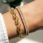 Model wearing gold bracelet stack with baguette diamond tennis bracelet and gold chunky bracelet