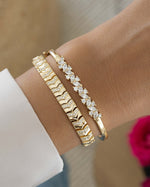 Model wearing minimalist gold bracelet stack featuring a bangle bracelet and a diamond tennis bracelet
