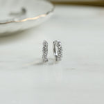 Closeup image of small silver hoop earrings with cubic zirconia diamonds