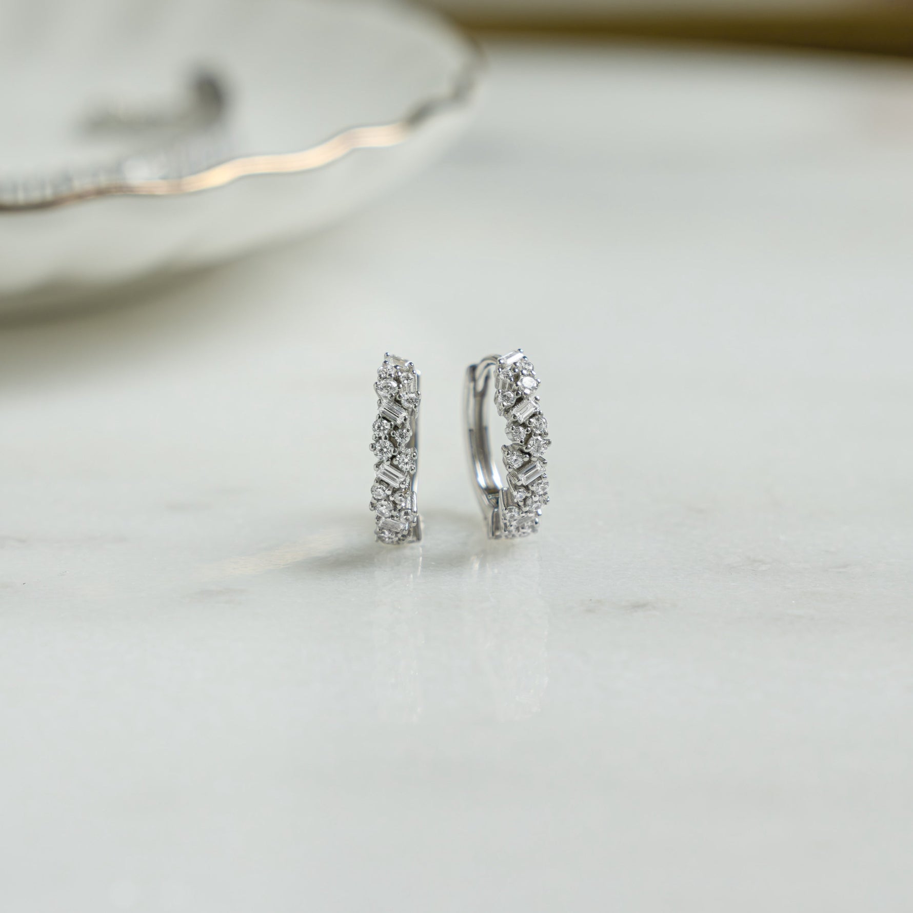 Closeup image of small silver hoop earrings with cubic zirconia diamonds