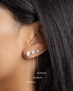 Sterling silver minimalist small earrings with a pear cut cubic zirconia stones featuring a 5x7mm diamond stud earring, a 4x6mm pear cut tiny stud and a 3x4m pear cut diamond dainty earring on models ear 