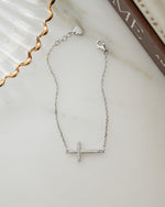 Closeup image of sterling silver chain bracelet with a diamond cross charm