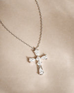 Silver chain cross pendant gemstone necklace on a beige background